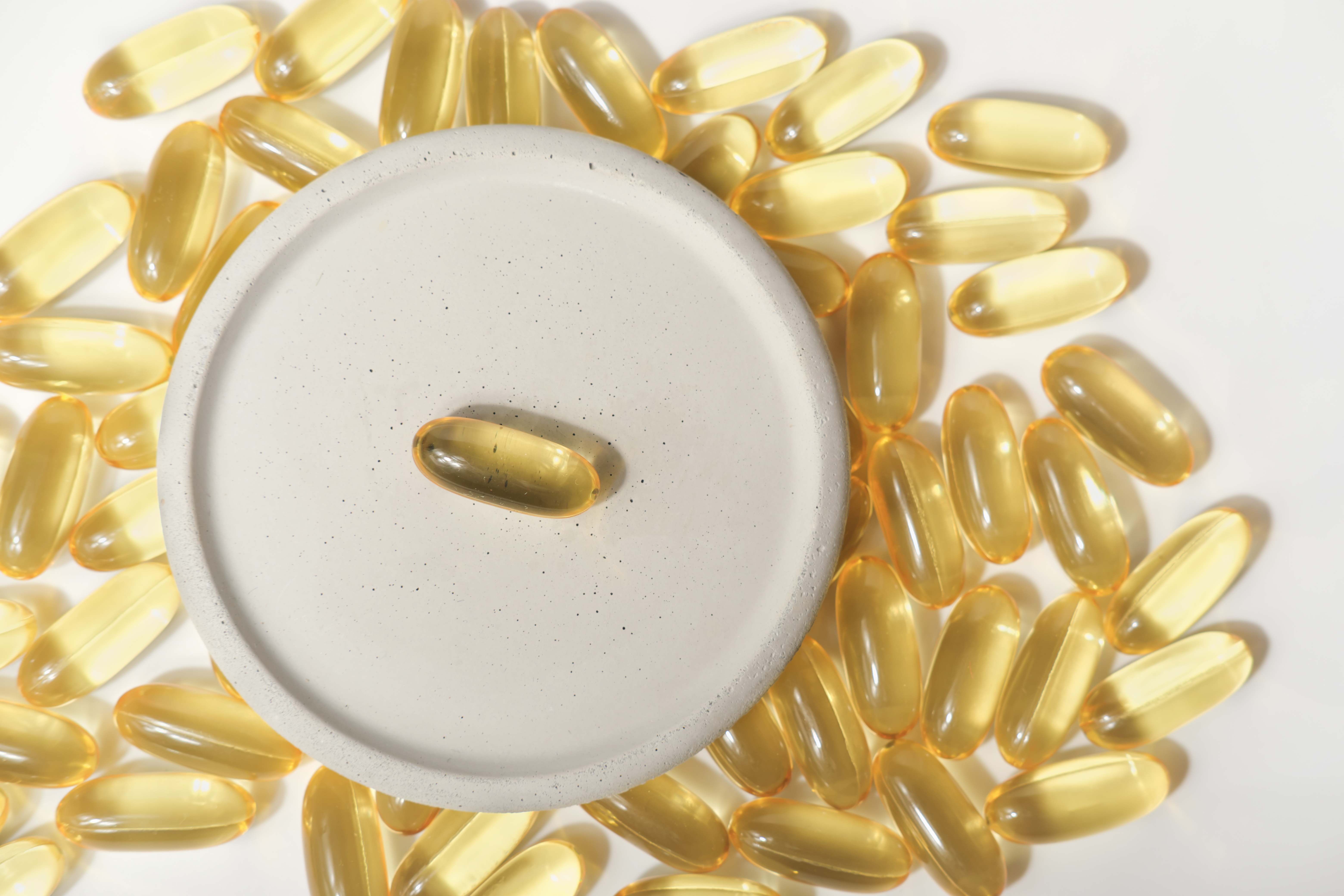 Fish oil omega 3 capsules on a grey plate. cod liver oil for heart and vascular support.