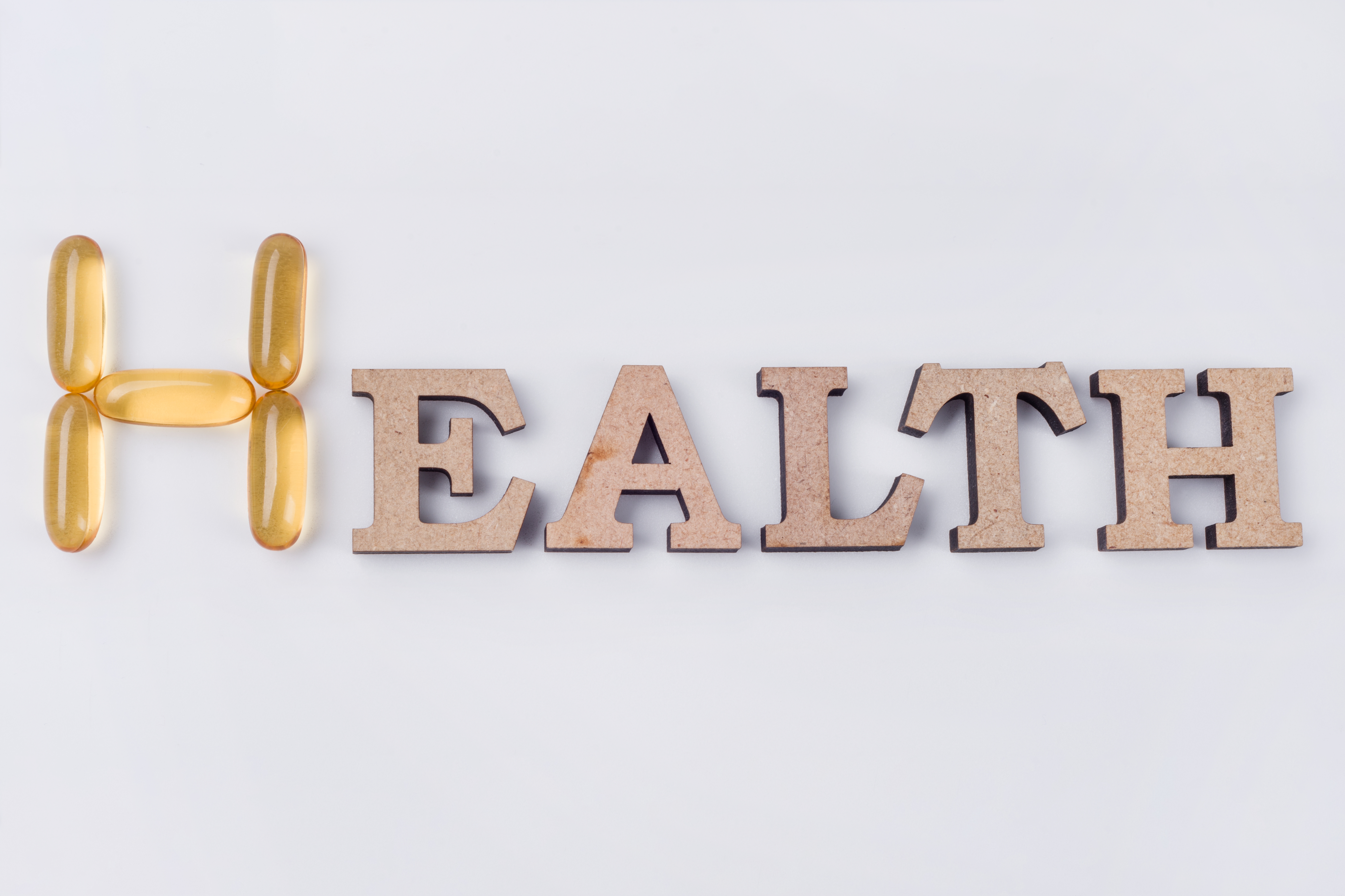Vitamin E Supplement. The word health is abstract wooden letters and capsules of fish oil